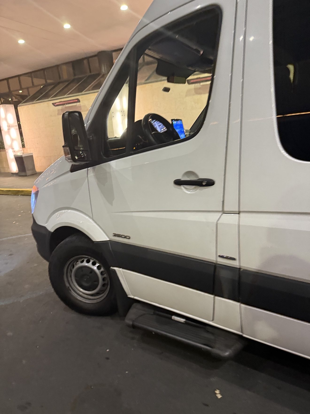 Sprinter van picking up passengers at a hotel entrance at night